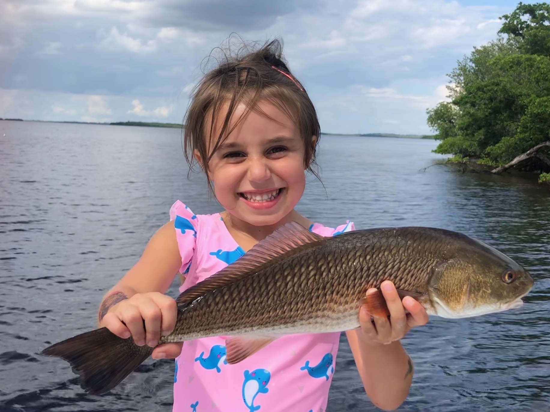 Photo of a child at Island Inn showing off a fish they caught.